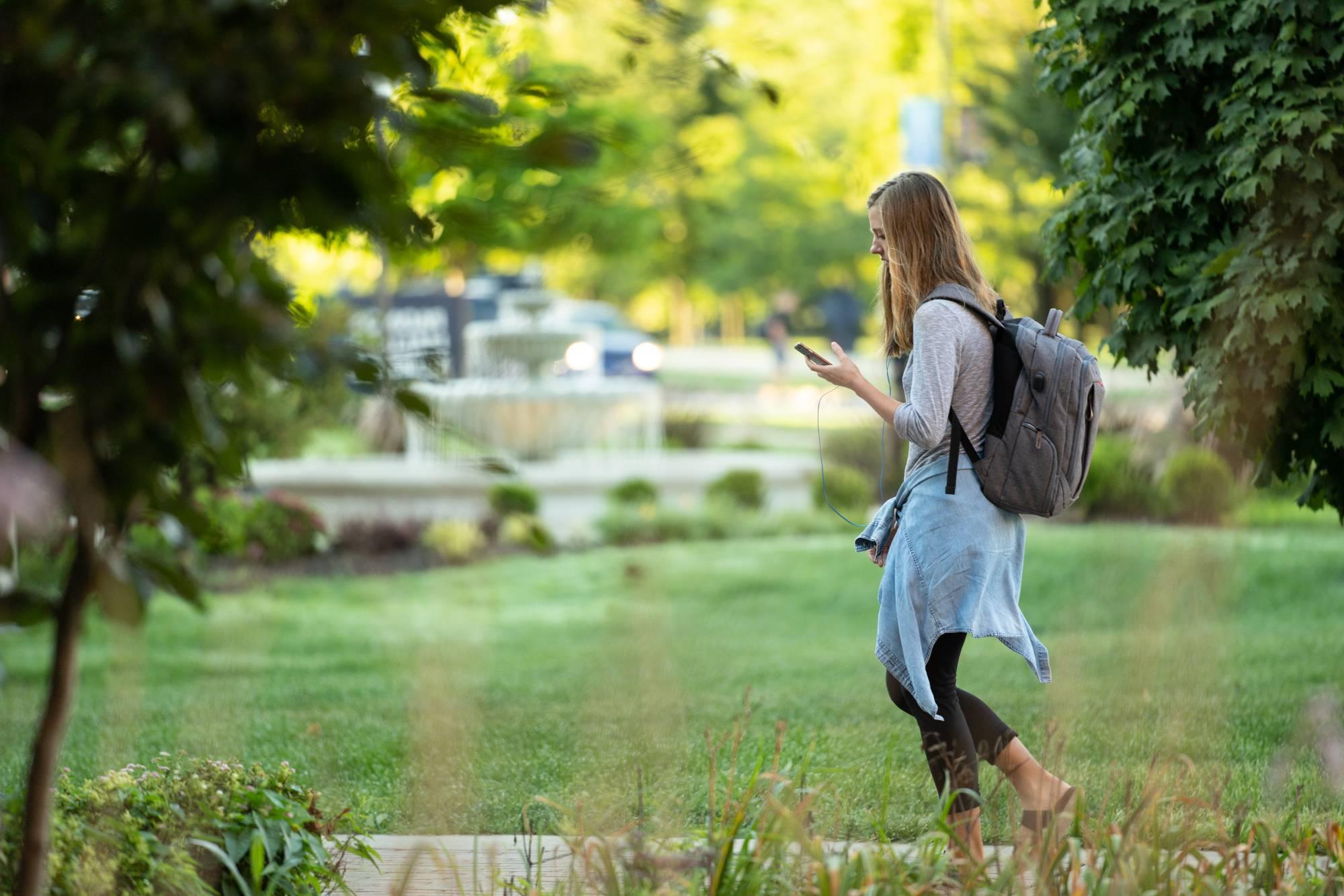 Student walking outside with white headphones in their ears